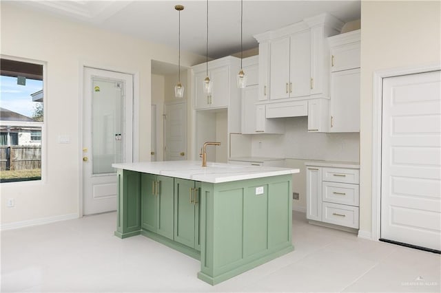 kitchen with a kitchen island with sink, light tile patterned floors, decorative light fixtures, white cabinets, and green cabinets