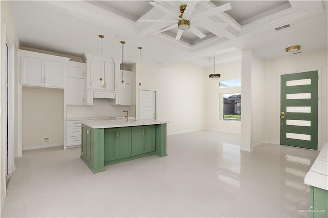 kitchen featuring pendant lighting, coffered ceiling, green cabinets, an island with sink, and white cabinetry