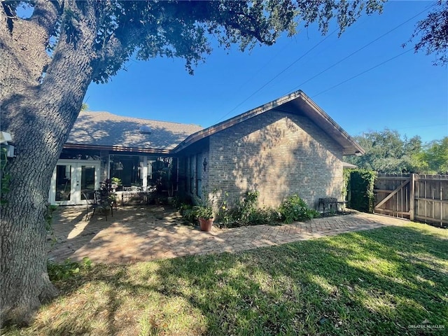 view of side of property with a patio, a yard, and french doors