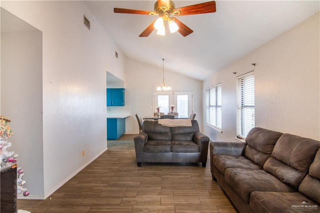 living room featuring ceiling fan with notable chandelier, vaulted ceiling, and dark hardwood / wood-style flooring