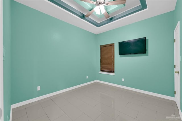 spare room featuring a tray ceiling, ceiling fan, and tile patterned floors