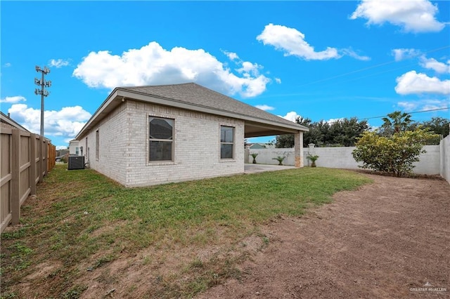 back of house featuring a lawn and central air condition unit