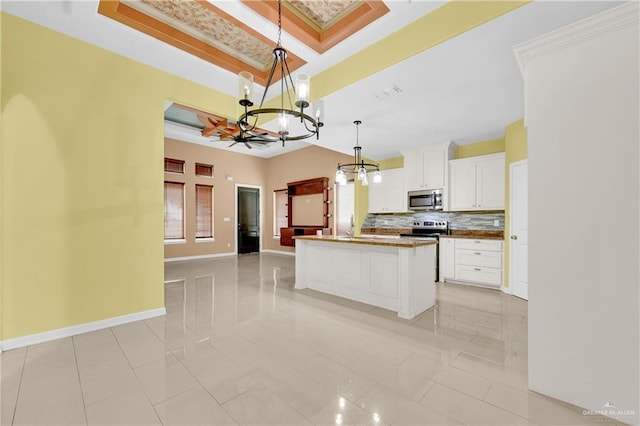 kitchen with ornamental molding, decorative light fixtures, a kitchen island, white cabinetry, and stainless steel appliances