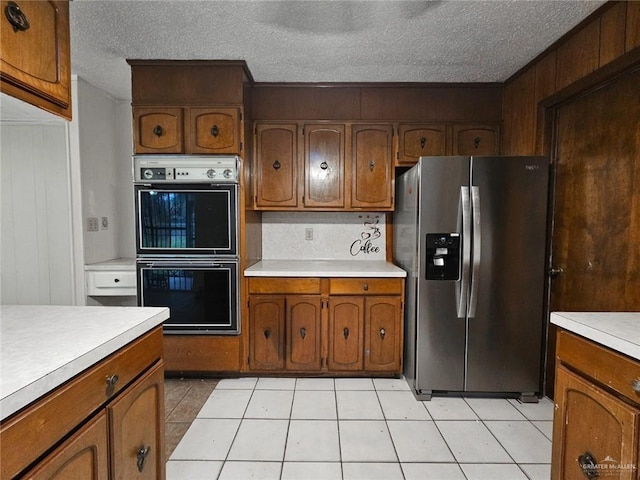 905 E Ithaca Ave, Mcallen, TX 78501 - kitchen featuring stainless steel refrigerator with ice dispenser, double wall oven, light countertops, brown cabinets, and a textured ceiling