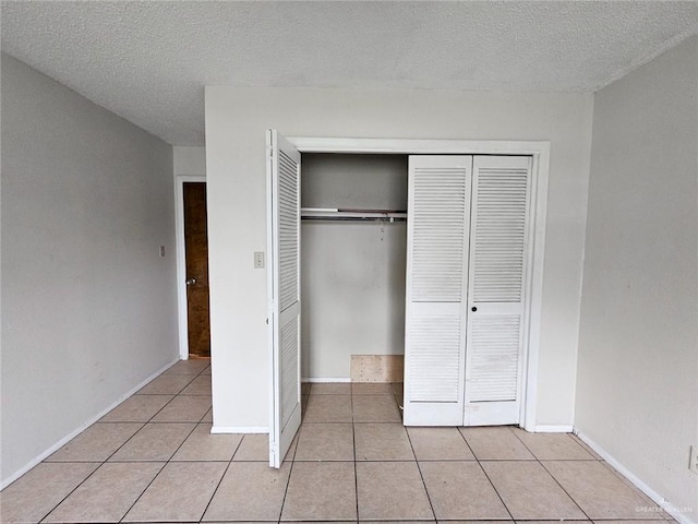 905 E Ithaca Ave, Mcallen, TX 78501 - unfurnished bedroom with tile patterned floors, a closet, a textured ceiling, and baseboards