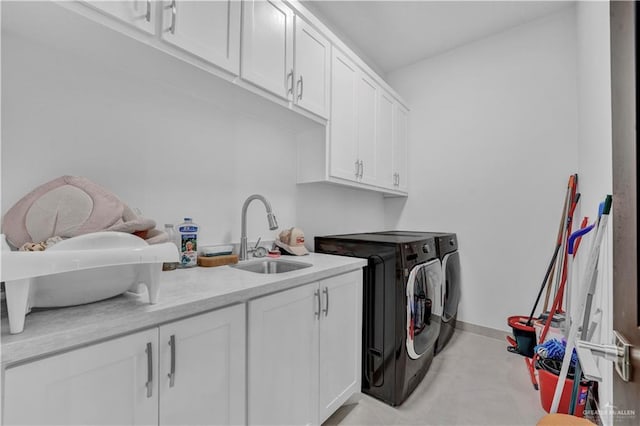 laundry room featuring washing machine and clothes dryer, cabinet space, baseboards, and a sink