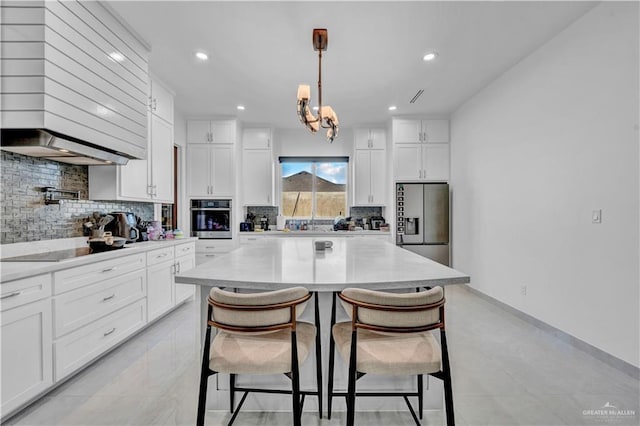 kitchen with stainless steel appliances, white cabinets, a kitchen breakfast bar, tasteful backsplash, and a chandelier