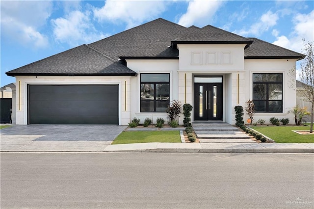 view of front of house featuring a garage, stucco siding, driveway, and a shingled roof