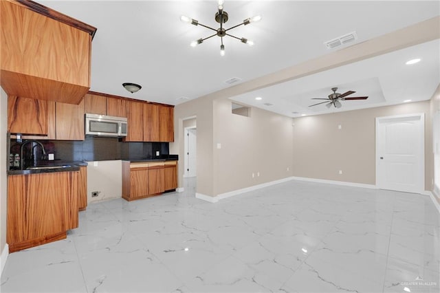 410 W 7th St, San Juan, TX 78589 - kitchen featuring stainless steel microwave, brown cabinets, tasteful backsplash, light marble finish floors, and recessed lighting