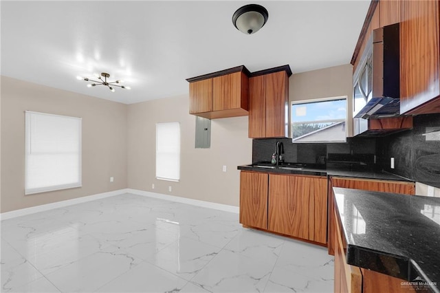 410 W 7th St, San Juan, TX 78589 - kitchen featuring light marble finish flooring, backsplash, brown cabinetry, a chandelier, and stainless steel microwave