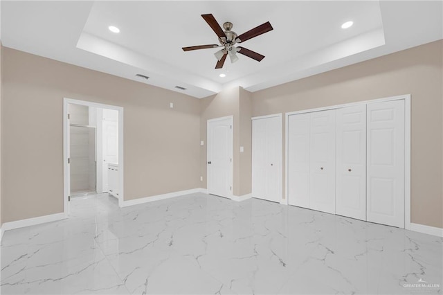 410 W 7th St, San Juan, TX 78589 - unfurnished bedroom featuring a tray ceiling, recessed lighting, two closets, ensuite bathroom, and light marble finish floors