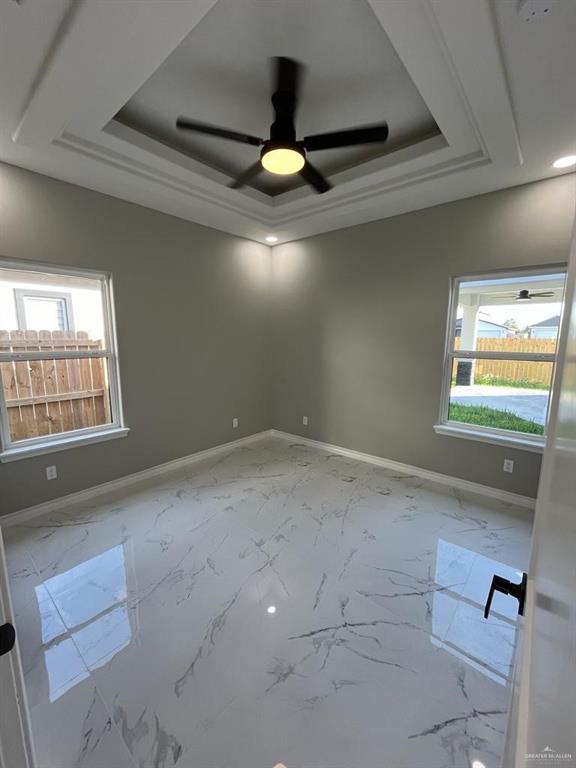 spare room featuring plenty of natural light, a raised ceiling, and ceiling fan