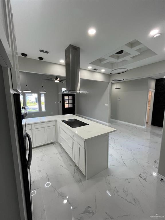 kitchen featuring white cabinets, island exhaust hood, kitchen peninsula, light stone countertops, and black electric cooktop