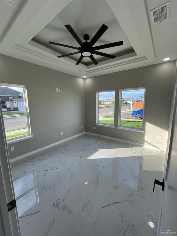 unfurnished room featuring ceiling fan, a tray ceiling, and a healthy amount of sunlight