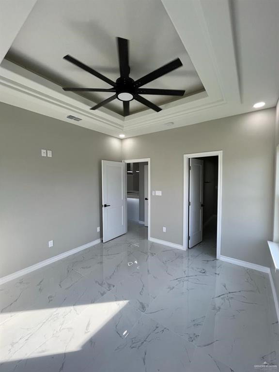 unfurnished bedroom featuring ceiling fan and a tray ceiling