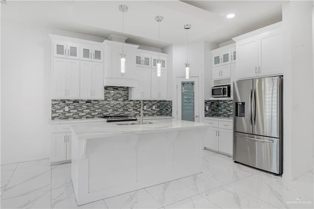 kitchen with stainless steel appliances, an island with sink, hanging light fixtures, and white cabinets