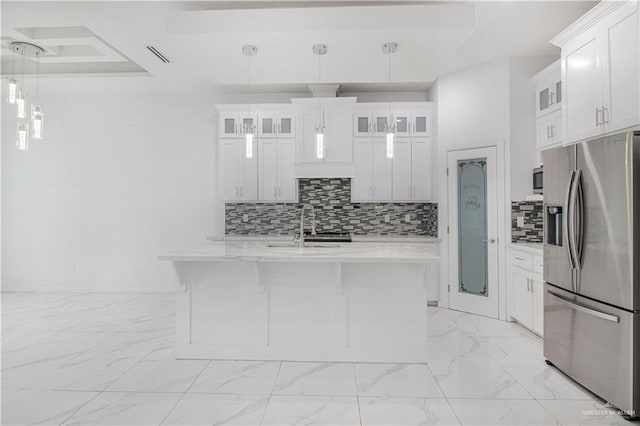 kitchen with stainless steel refrigerator with ice dispenser, pendant lighting, sink, and white cabinets