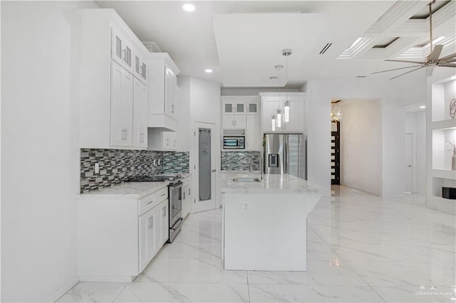 kitchen with white cabinetry, hanging light fixtures, appliances with stainless steel finishes, a kitchen island, and ceiling fan