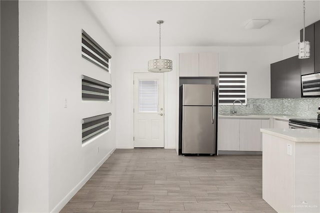 907 W Carmel Ave, Pharr, TX 78577 - kitchen with appliances with stainless steel finishes, light countertops, light wood-type flooring, hanging light fixtures, and a sink