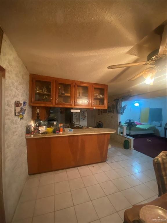 kitchen with kitchen peninsula, a textured ceiling, ceiling fan, and light tile patterned flooring