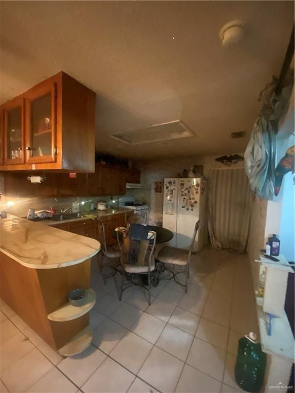 kitchen with kitchen peninsula, light tile patterned floors, and white fridge with ice dispenser