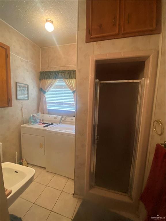 bathroom featuring tile patterned floors, a shower with shower door, a textured ceiling, and washing machine and clothes dryer