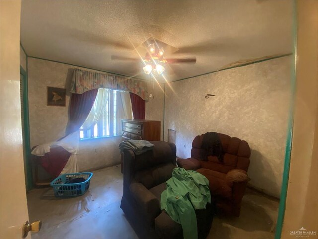 living area featuring ceiling fan, a textured ceiling, and concrete floors