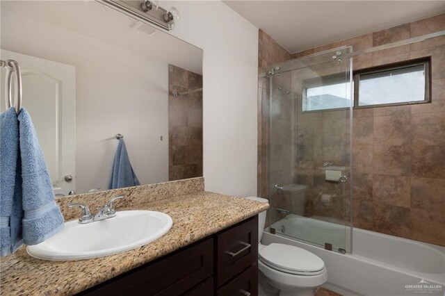 full bathroom with toilet, enclosed tub / shower combo, and vanity