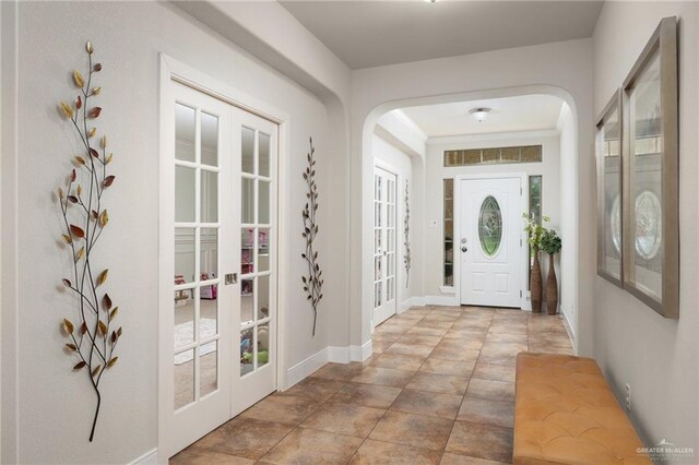 entryway featuring french doors, baseboards, and arched walkways