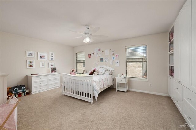 bedroom featuring light colored carpet, a ceiling fan, and multiple windows