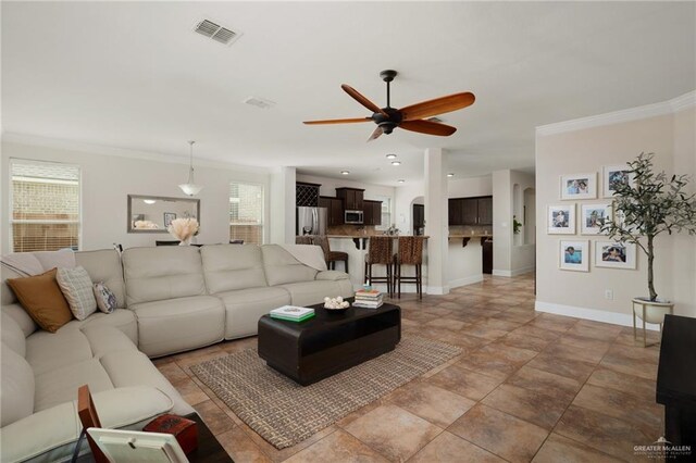 living room featuring a wealth of natural light, visible vents, ceiling fan, and baseboards