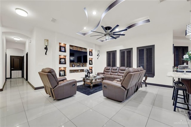 living area with ceiling fan, light tile patterned flooring, arched walkways, and baseboards