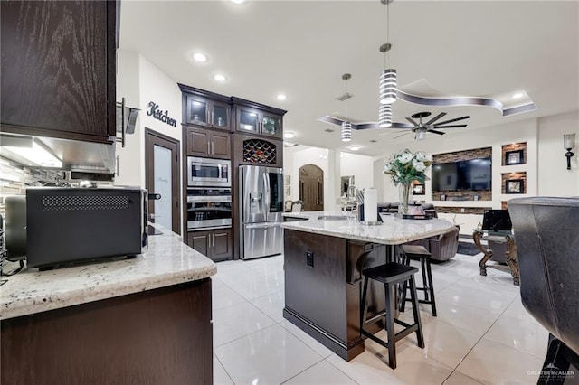 kitchen featuring stainless steel appliances, open floor plan, light tile patterned flooring, and tasteful backsplash