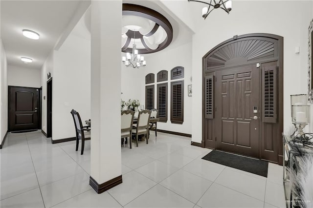 entryway featuring light tile patterned floors, baseboards, and a chandelier