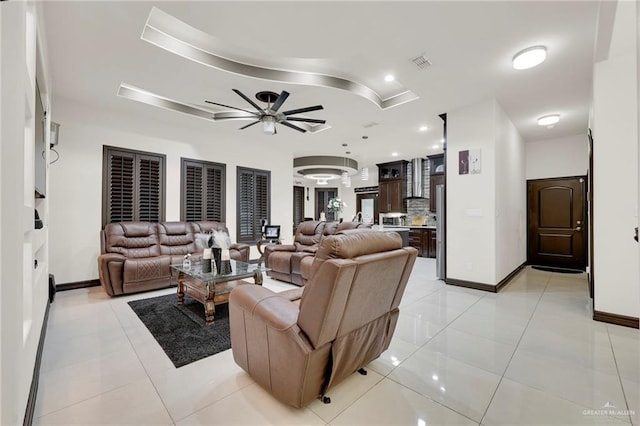 living area with light tile patterned floors, baseboards, a raised ceiling, a ceiling fan, and recessed lighting