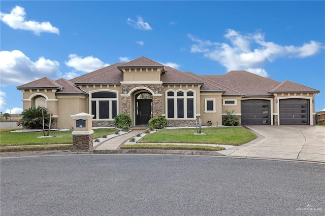 mediterranean / spanish house featuring a garage, concrete driveway, stone siding, stucco siding, and a front yard