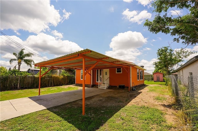 24834 Birch St, San Benito, TX 78586 - back of house with entry steps, concrete driveway, a carport, an outdoor structure, and a shed