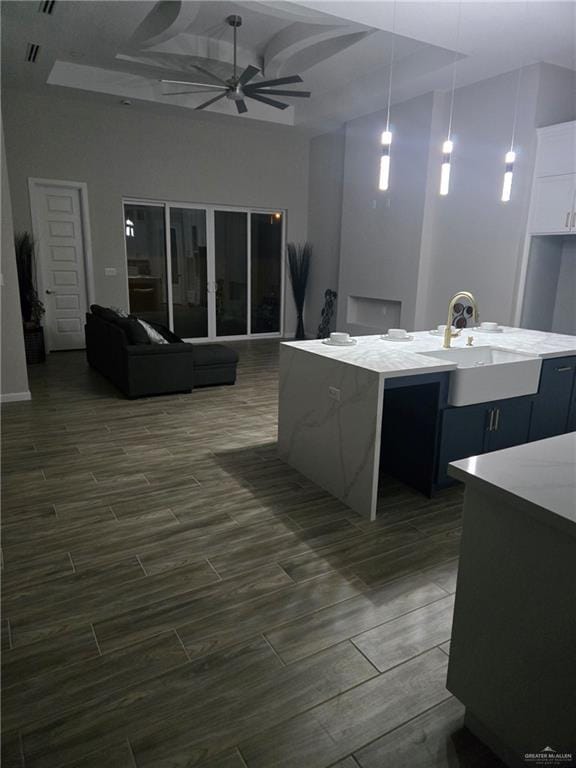 kitchen featuring sink, white cabinetry, hanging light fixtures, a center island with sink, and ceiling fan