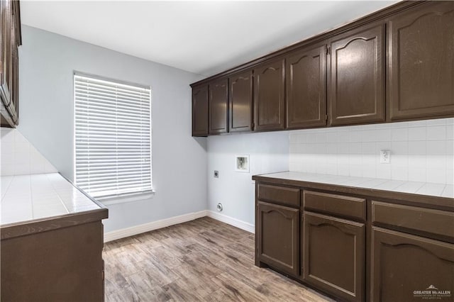 laundry room with baseboards, washer hookup, light wood-type flooring, cabinet space, and electric dryer hookup
