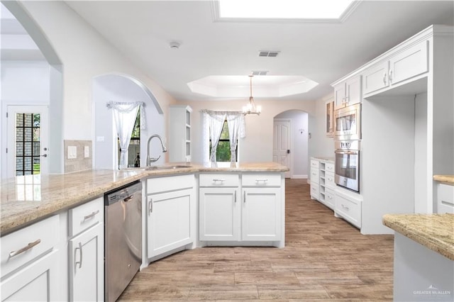 kitchen with visible vents, a sink, light wood-type flooring, a tray ceiling, and stainless steel appliances