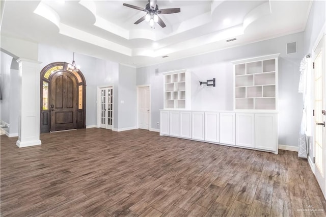 interior space with decorative columns, dark wood finished floors, a ceiling fan, and a raised ceiling