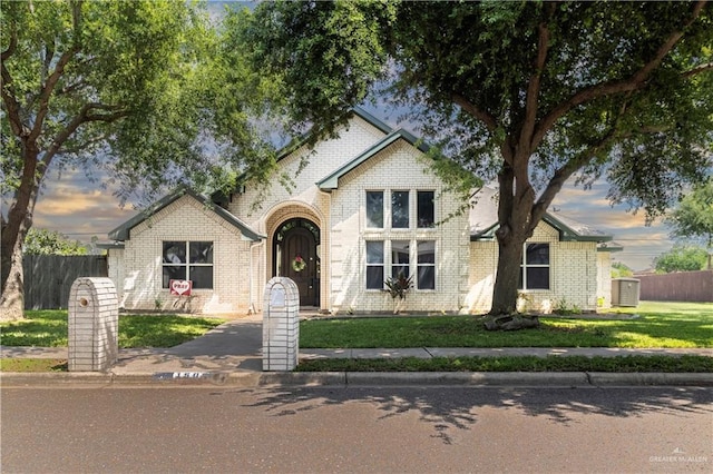 traditional home featuring a front yard, fence, and brick siding