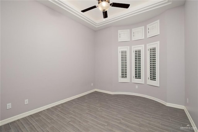 spare room featuring a tray ceiling, ceiling fan, and wood-type flooring