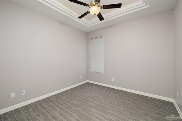 unfurnished room featuring a tray ceiling, ceiling fan, crown molding, and wood-type flooring