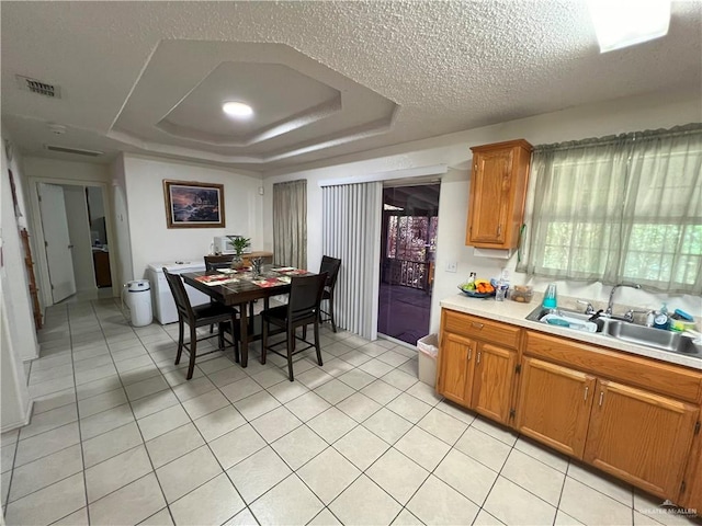 kitchen featuring light tile patterned floors, a textured ceiling, a tray ceiling, and sink