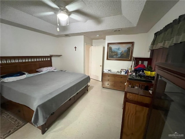 bedroom featuring a raised ceiling, ceiling fan, and a textured ceiling