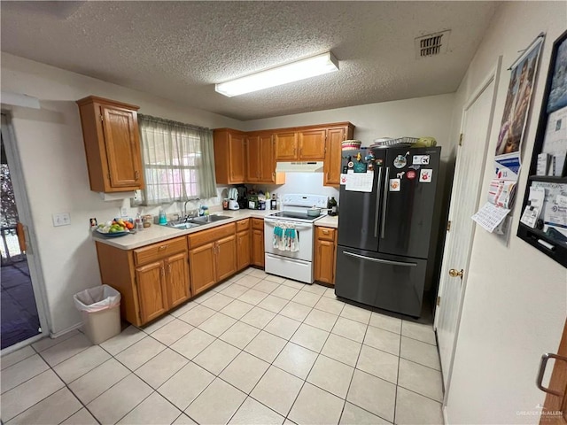 kitchen with sink, electric range, a textured ceiling, light tile patterned flooring, and stainless steel refrigerator