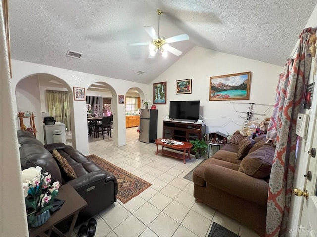 tiled living room with a textured ceiling, ceiling fan, and lofted ceiling