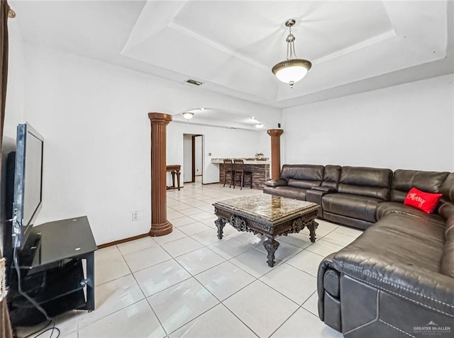 tiled living room featuring a raised ceiling and ornate columns