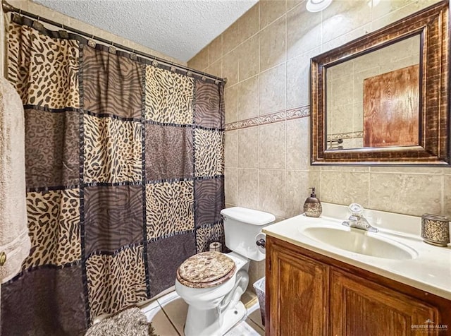 bathroom with vanity, a textured ceiling, toilet, and tile walls